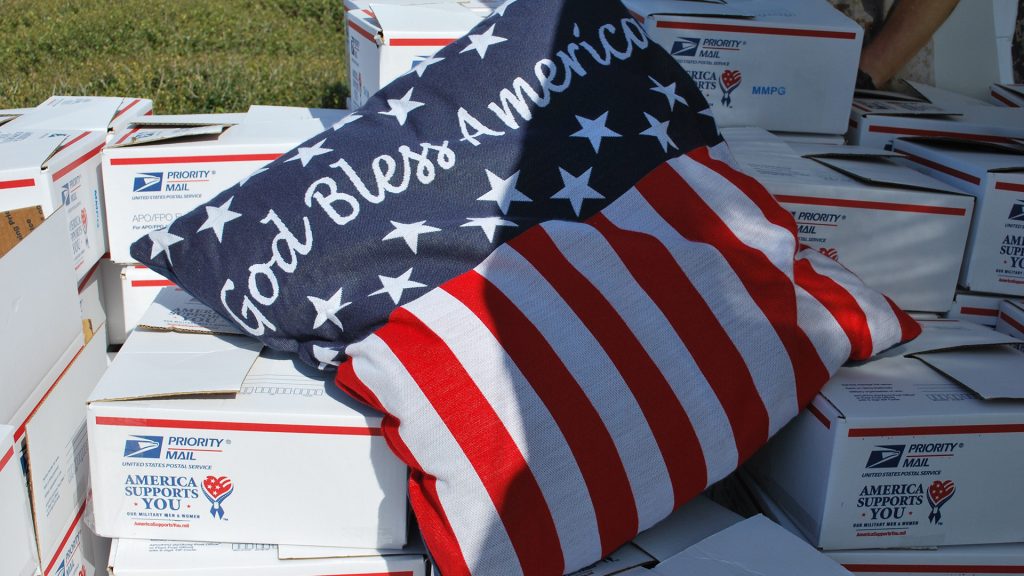God Bless America Pillow laid out on Gift Boxes for a holiday fundraising program sponsored by Military Moms Prayer Group, for deployed U.S. troops.
